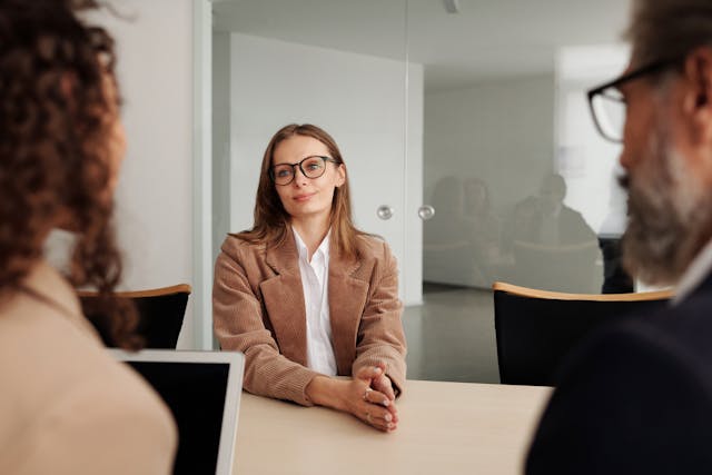 Illustrative image Woman in Brown Blazer seated beside Table used in Accordemy®'s training on Inclusive Recruitment and Selection Practices