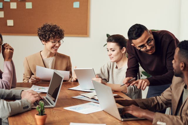 Illustrative image of Group of People Gathered Around Wooden Table used in Accordemy®'s training on HR's Role in HR in Mergers and Acquisitions
