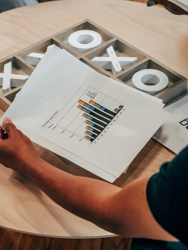Illustrative image Person Holding White Printer Paper on Wooden Table used in Accordemy®'s training on Agile Performance Management