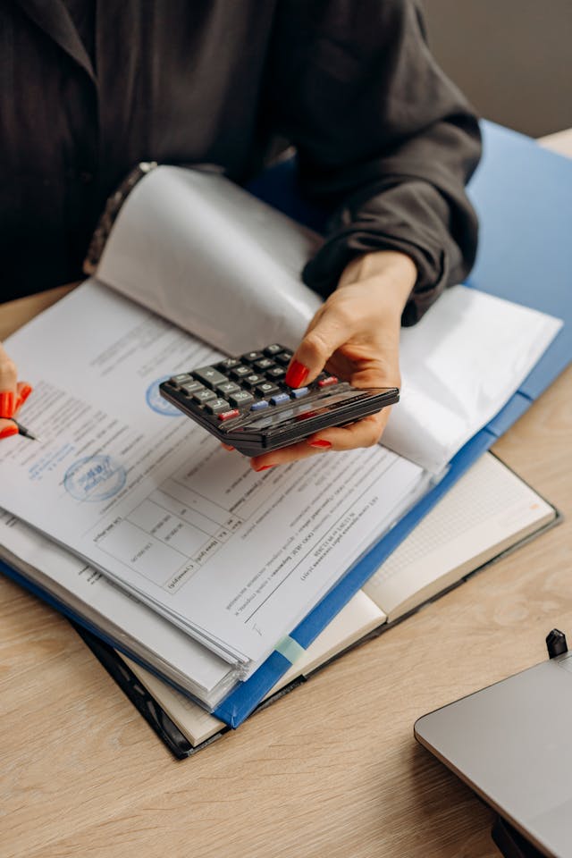 Illustrative image Person Holding Calculator Checking On Documents used in Accordemy®'s training on Job Analysis and Job Description Preparation