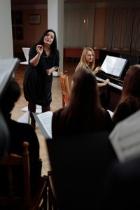 Illustrative image of A Woman Standing Next to a Woman Playing Piano used in Accordemy®'s training on Leading to Maximize Performance.