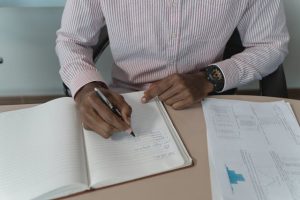 Illustrative image A Person in Long Sleeves Writing on a Notebook used in Accordemy®'s training on Job Analysis and Job Description Preparation