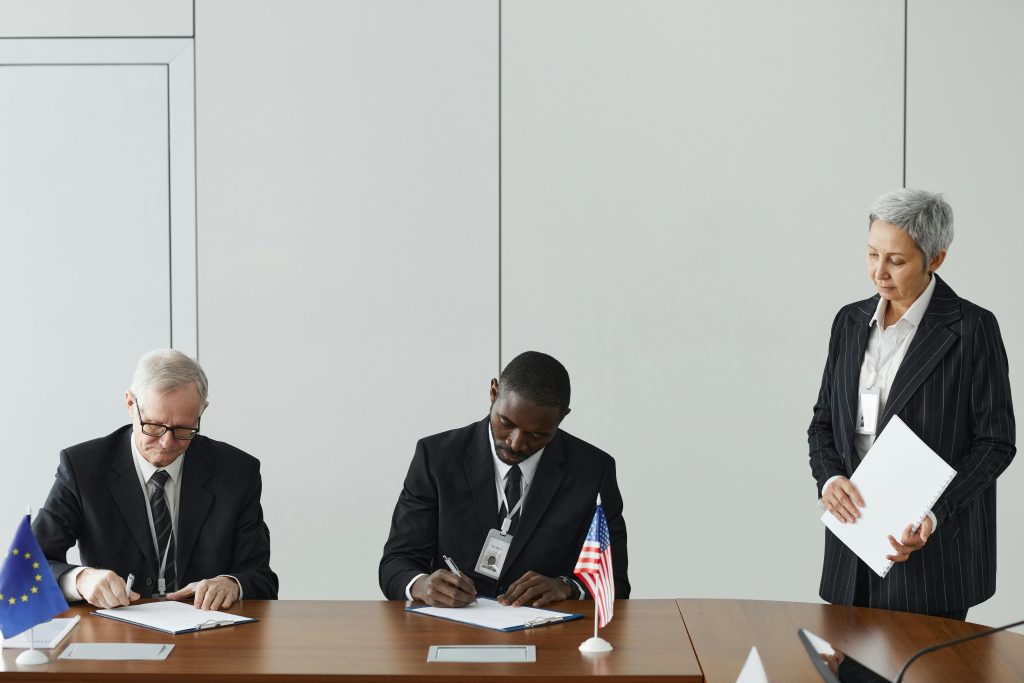 Illustrative image of A Woman Standing Beside Two Men Signing Documents
 used in Accordemy®'s training on Strategic Media Relations.