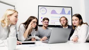 Illustrative image Man and Woman Sitting at Table With Macbook used in Accordemy®'s training on Project Management Office