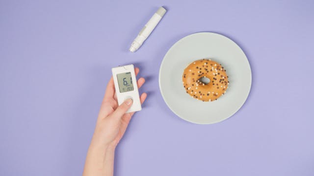 Illustrative image A Hand Holding a Glucometer Beside a Doughnut used in Accordemy®'s training on Health Risk Assessment and Management