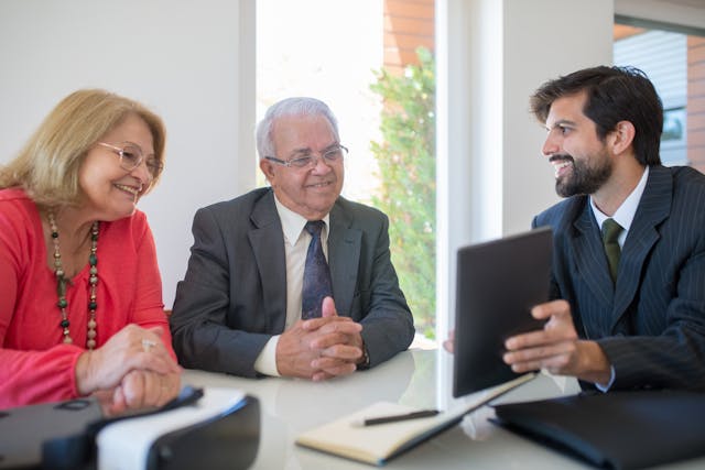 Illustrative image Man in Black Suit Jacket Sitting Beside a Man in Gray Suit used in Accordemy®'s training on Meeting Management in Land and Real Estate Affairs