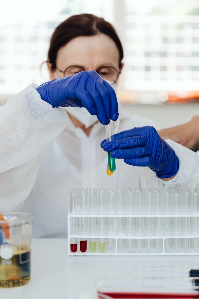 Illustrative image A Woman in Medical Gloves Holding Test Tubes with Liquid used in Accordemy®'s training on Health Informatics