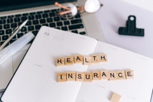 Illustrative image Wooden Scrabble Tiles on White Notebook used in Accordemy®'s training on Health Finance and Health Insurance Systems