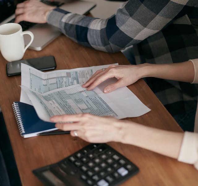 Illustrative image A Person Holding Tax Forms on Wooden Table used in Accordemy®'s training on The effective use of AI in Land Affairs Administration