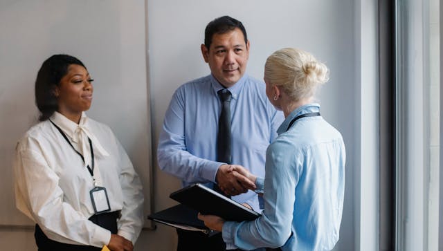 Illustrative image Cheerful multiethnic colleagues having deal in office used in Accordemy®'s training on Advanced Contract Negotiation Strategies