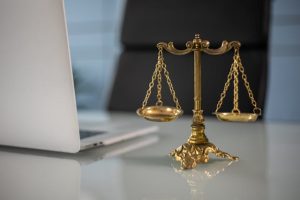 Illustrative image A Golden Balance Scale beside a Laptop used in Accordemy®'s training on Humanitarian Law and Ethics