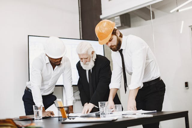 Illustrative image Businessman and Architects Looking at Blueprints in an Office used in Accordemy®'s training on Advanced Project Management for Humanitarian Organizations
