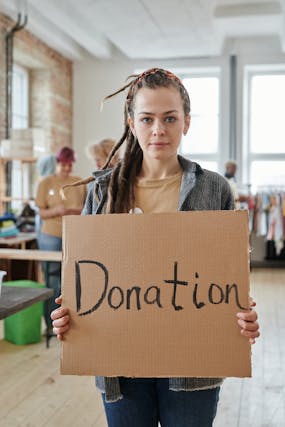 Illustrative image A Woman Holding a Cardboard with Inscription used in Accordemy®'s training on Fundraising for non-profit organizations
