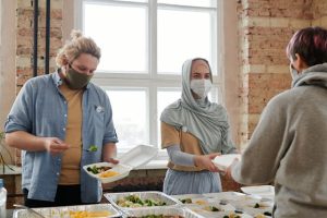 Illustrative image Volunteers Giving Out Meals Wearing Face Masks used in Accordemy®'s training on Trauma-Informed Care in Humanitarian Settings