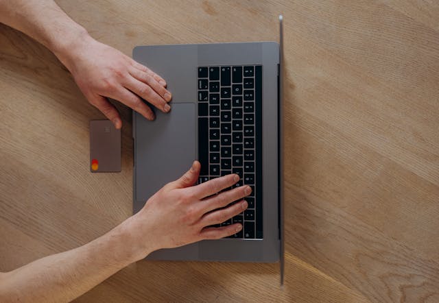 Illustrative image A Person Using a Laptop Beside a Credit Card on a Wooden Table used in Accordemy®'s training on Customer Service