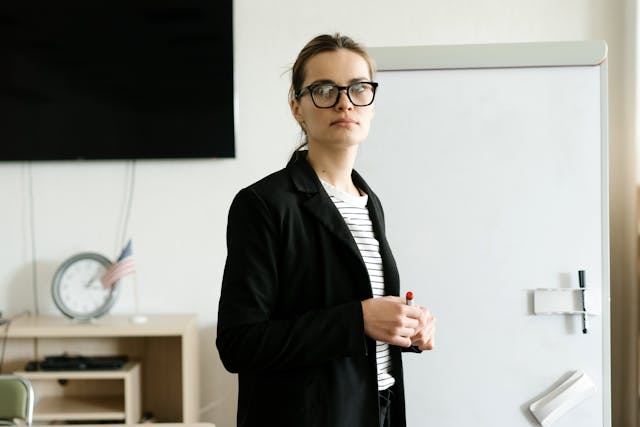 Illustrative image A Woman in a Black Blazer Standing beside a Whiteboard used in Accordemy®'s training on Training Monitoring and Evaluation Expert