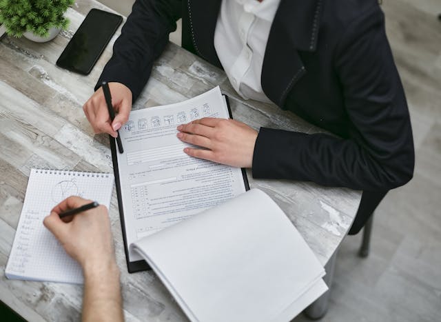 Illustrative image Two People Sitting at Desk with Documents used in Accordemy®'s training on Effective Delegation for Administrative