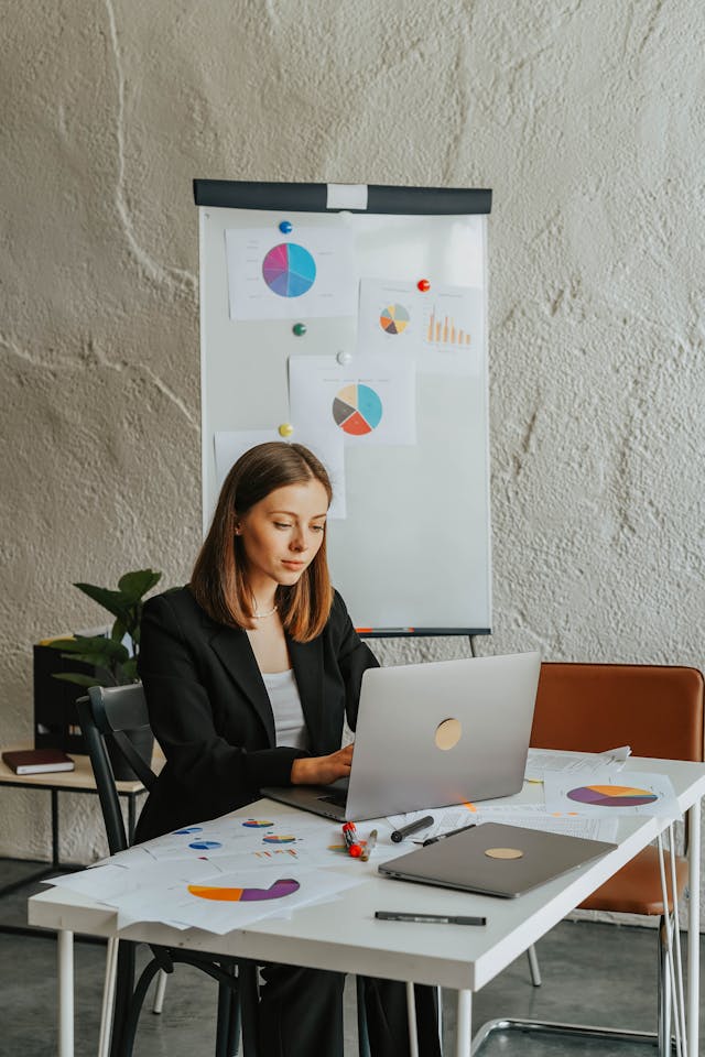 Illustrative image Woman in Black Blazer at the Table Using Laptop used in Accordemy®'s training on Accordemy® Certified Trainer Level 1