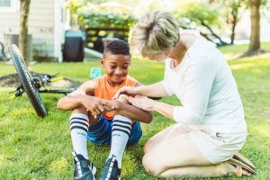 Illustrative image Mom Putting Band-Aid on Her Son's Knee used in Accordemy®'s training on Child Protection in Emergencies