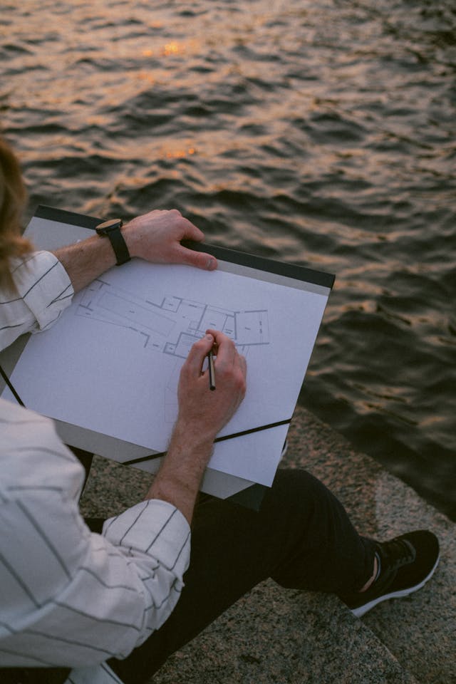 Illustrative image A Man Drawing by the Seawall used in Accordemy®'s training on Writing Winning Proposals for Relief and Development Projects