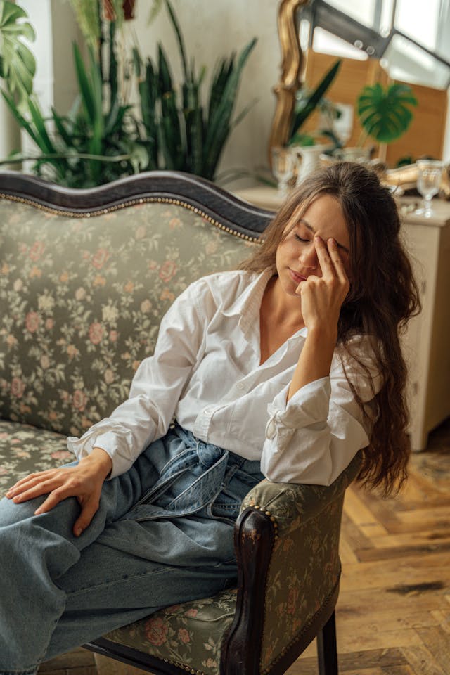 Illustrative image Woman in White Dress Shirt and Blue Denim Jeans Sitting on Couch used in Accordemy®'s training on Mental Health in Humanitarian Crises