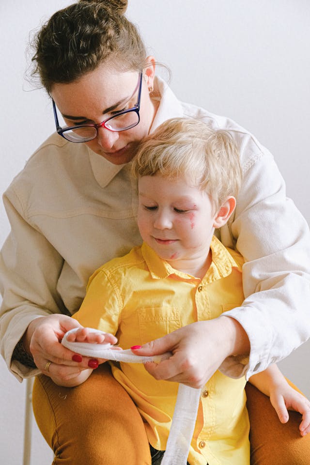 Illustrative image Woman Putting Bandage On Boy's Hand used in Accordemy®'s training on Child Protection in Emergencies