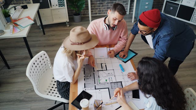 Illustrative image Four people sitting around a table looking at blueprints used in Accordemy®'s training on Humanitarian Coordination and Leadership