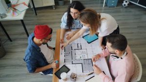 Illustrative image Four people sitting around a table looking at blueprints used in Accordemy®'s training on Humanitarian Coordination and Leadership