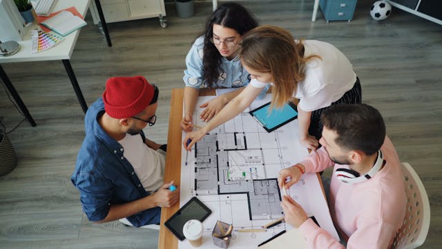 Illustrative image Four people sitting around a table looking at blueprints used in Accordemy®'s training on Humanitarian Coordination and Leadership