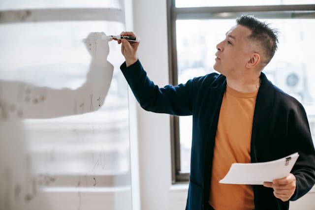 Illustrative image Photo Of Man Writing On White Board  used in Accordemy®'s training on Essential ToT (Level 1): Foundational Training of Trainers Course