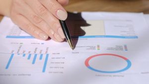 Illustrative image Person Holding Black Pen on White Printer Paper used in Accordemy®'s training on Review of Financial Accounting and Detecting Fraud
