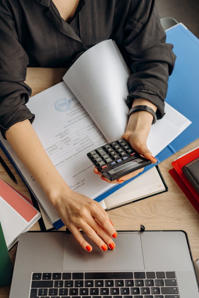 Illustrative image Person Holding Black Calculator While Using Laptop
 used in Accordemy®'s training on Internal Control and Audit